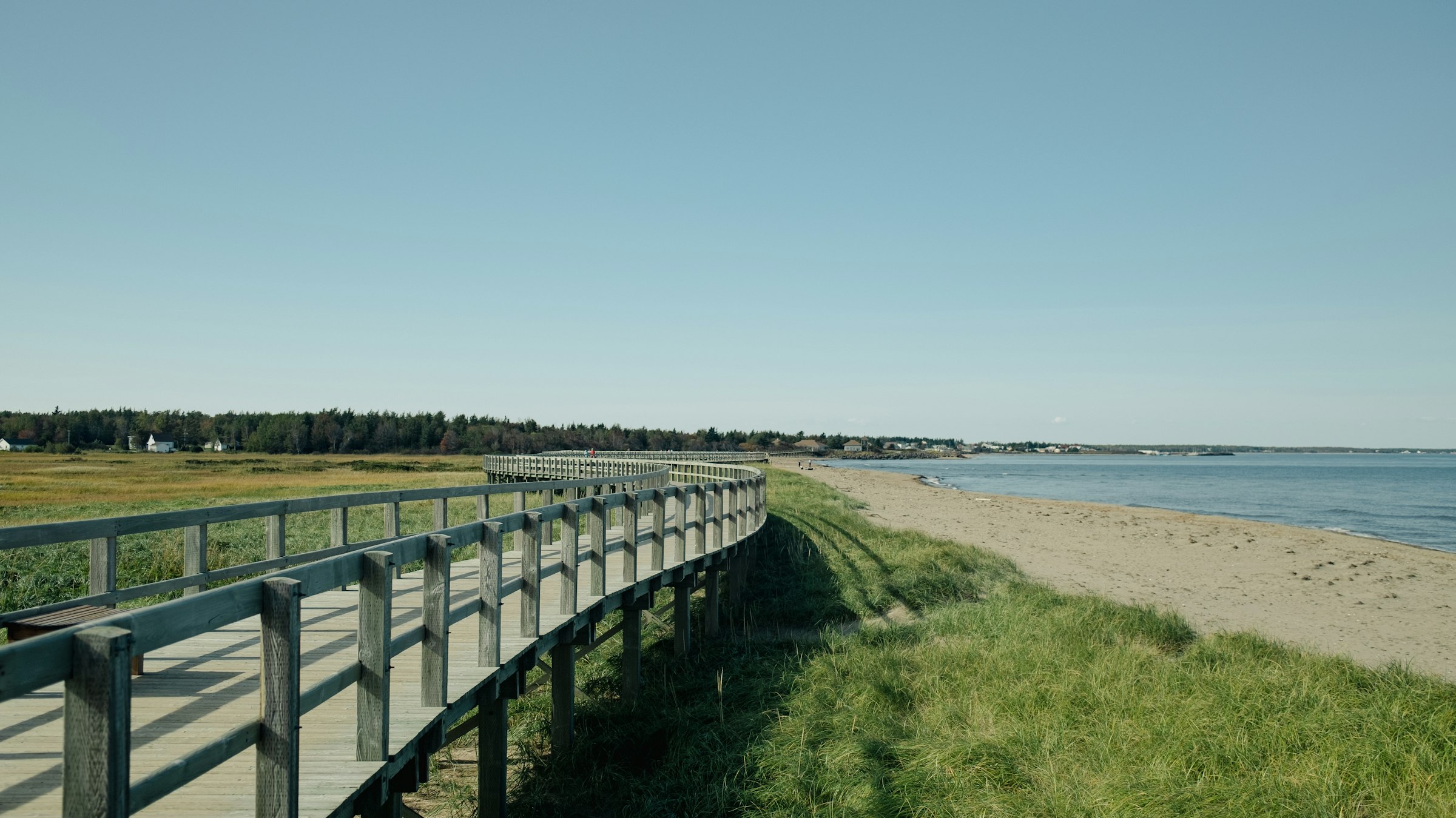 A wooden boardwalk running along a sandy beach